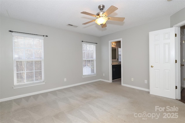 unfurnished bedroom featuring ensuite bathroom, ceiling fan, light colored carpet, and a textured ceiling