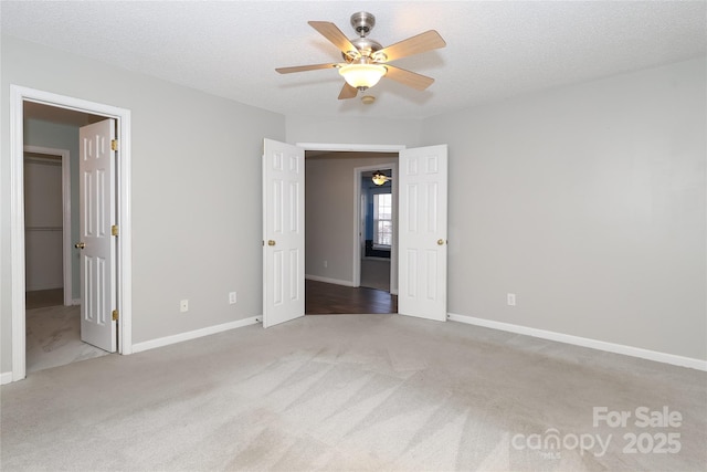 unfurnished bedroom featuring ceiling fan, light colored carpet, and a textured ceiling