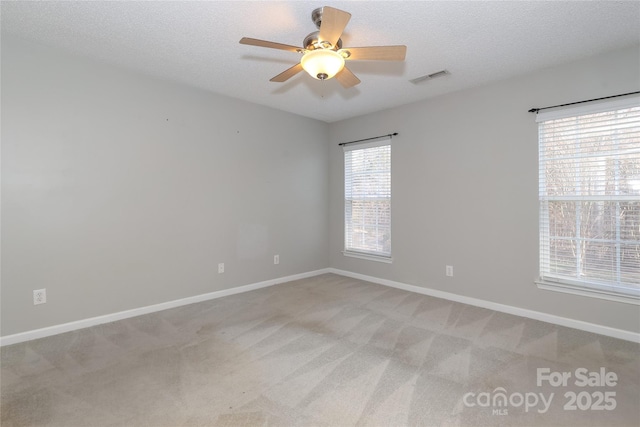 spare room featuring a textured ceiling, ceiling fan, and light carpet