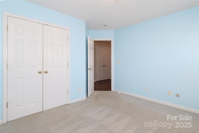 unfurnished bedroom featuring a closet and light colored carpet