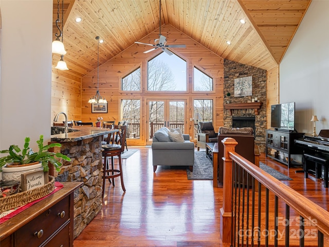 living room featuring hardwood / wood-style floors, high vaulted ceiling, ceiling fan with notable chandelier, sink, and wood ceiling