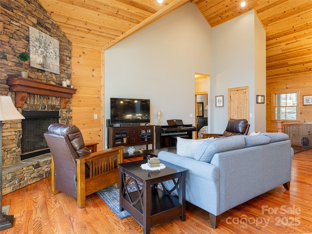 living room featuring light wood-type flooring, wooden walls, high vaulted ceiling, wooden ceiling, and a fireplace