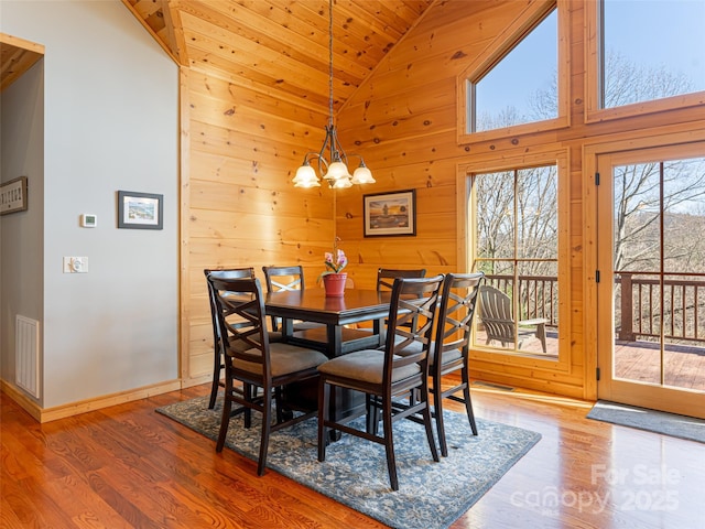 dining area with hardwood / wood-style floors, wooden ceiling, high vaulted ceiling, and a chandelier