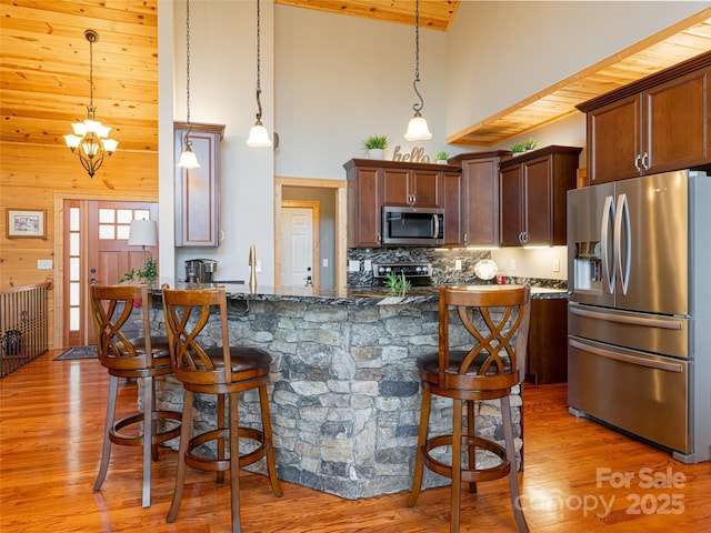 kitchen featuring pendant lighting, high vaulted ceiling, and appliances with stainless steel finishes