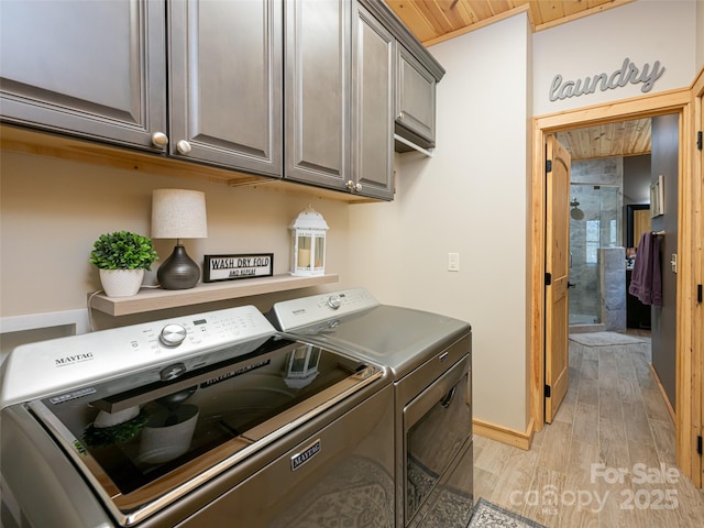 laundry area with washing machine and dryer, cabinets, and light hardwood / wood-style floors