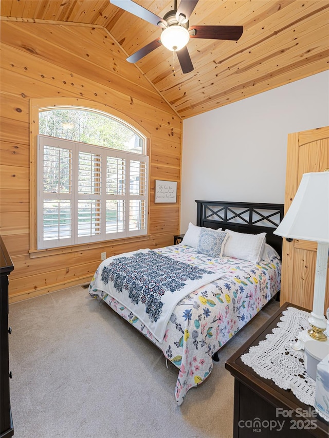 carpeted bedroom with vaulted ceiling, ceiling fan, wooden ceiling, and wood walls