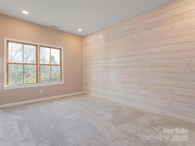 unfurnished room with wood walls and light carpet