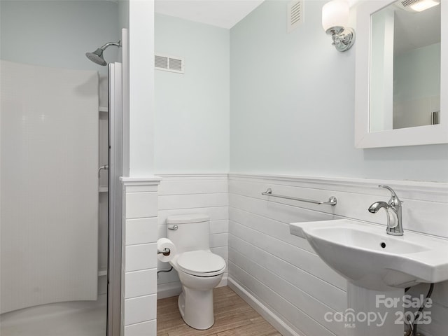 bathroom with walk in shower, sink, hardwood / wood-style floors, and toilet