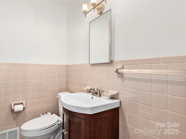 bathroom with vanity, toilet, and tile walls