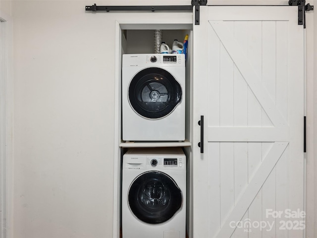 laundry area featuring a barn door and stacked washing maching and dryer