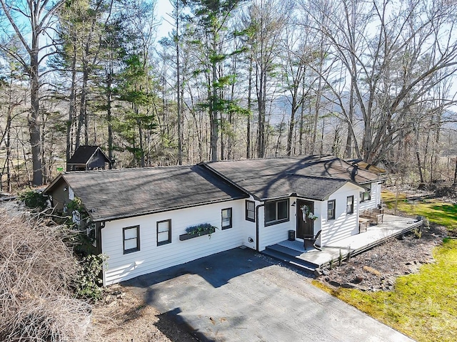 ranch-style home featuring aphalt driveway and roof with shingles