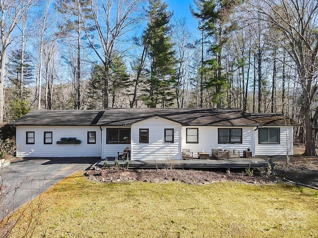 single story home featuring driveway, a deck, and a front yard