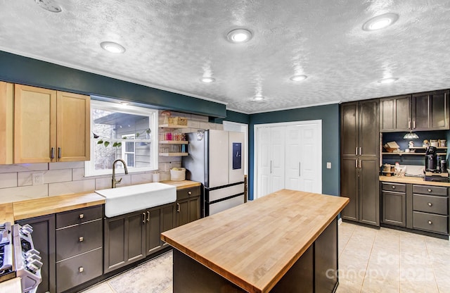 kitchen featuring freestanding refrigerator, wooden counters, a sink, and open shelves