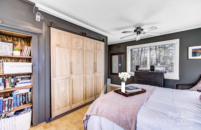 bedroom with ceiling fan, a closet, crown molding, and a barn door