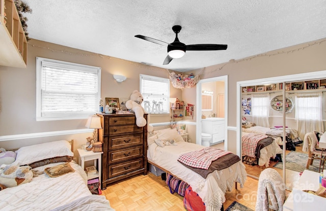 bedroom featuring multiple windows, ceiling fan, a textured ceiling, and ensuite bathroom