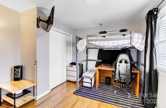 bedroom featuring visible vents, a closet, baseboards, and wood finished floors