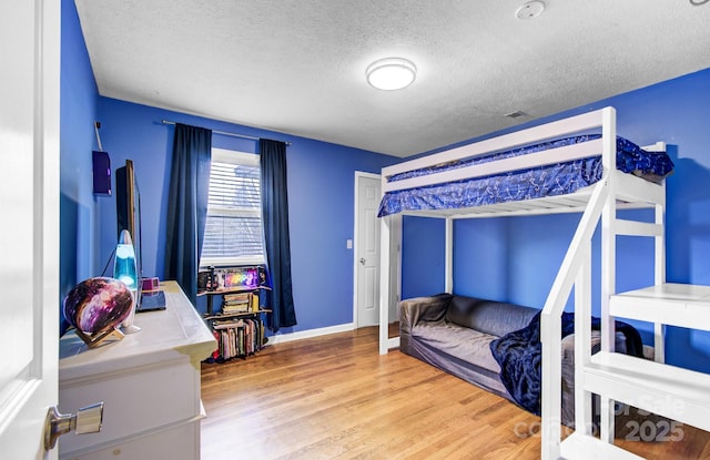 bedroom with a textured ceiling, wood finished floors, and baseboards