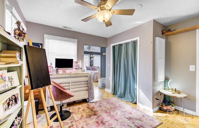 bedroom featuring a textured ceiling, ceiling fan, visible vents, and baseboards