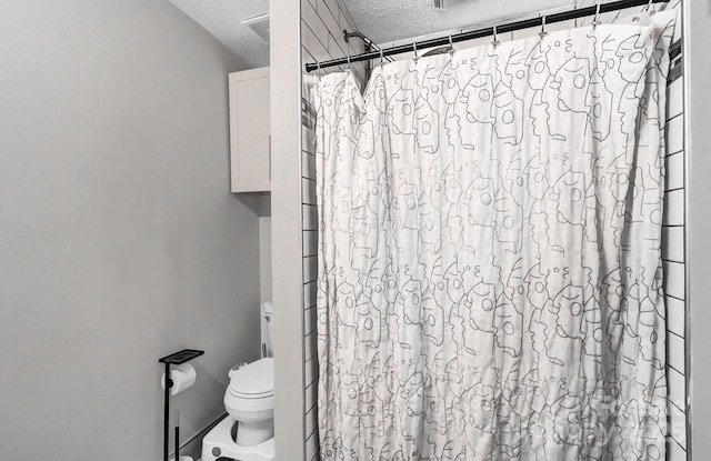 bathroom with toilet, visible vents, a textured ceiling, and a shower with shower curtain