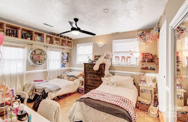 bedroom featuring a ceiling fan, visible vents, and a textured ceiling