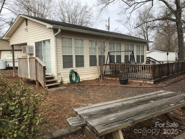 rear view of house with a deck and a wall unit AC