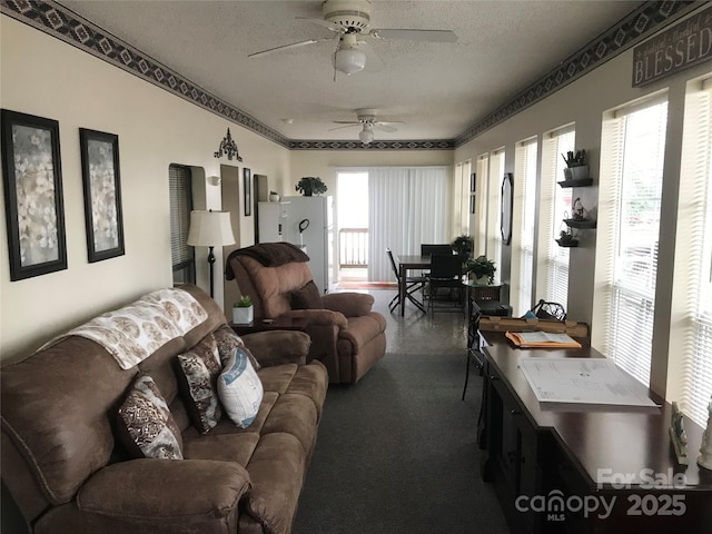 living room featuring ceiling fan, a textured ceiling, and a wealth of natural light