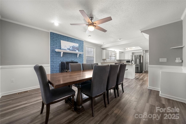 dining room with visible vents, a textured ceiling, crown molding, and wood finished floors