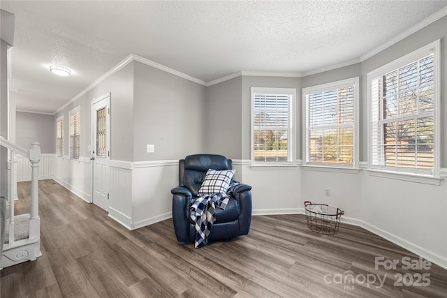 sitting room with crown molding, stairway, wood finished floors, and a wainscoted wall