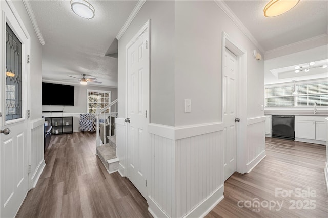 hall with stairway, a textured ceiling, wood finished floors, and ornamental molding