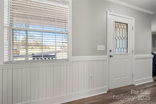 entryway with a wainscoted wall, wood finished floors, and crown molding