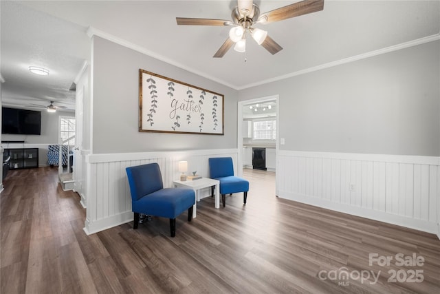 living area featuring a wainscoted wall, wood finished floors, and crown molding