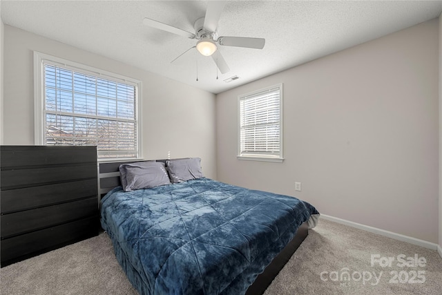 bedroom featuring visible vents, baseboards, ceiling fan, carpet flooring, and a textured ceiling