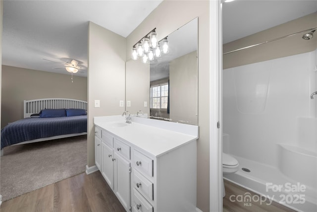 full bath with toilet, wood finished floors, vanity, a shower, and a ceiling fan