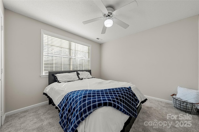 bedroom featuring ceiling fan, carpet, baseboards, and a textured ceiling