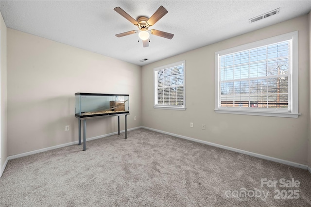 carpeted spare room featuring ceiling fan, baseboards, visible vents, and a textured ceiling