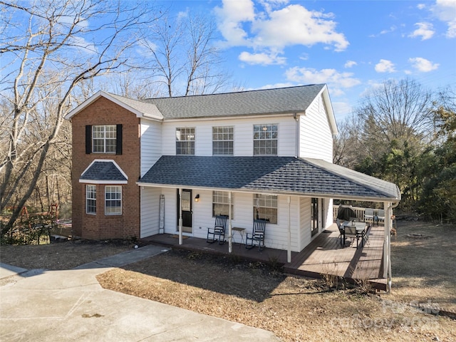 view of front of house featuring brick siding, covered porch, and roof with shingles