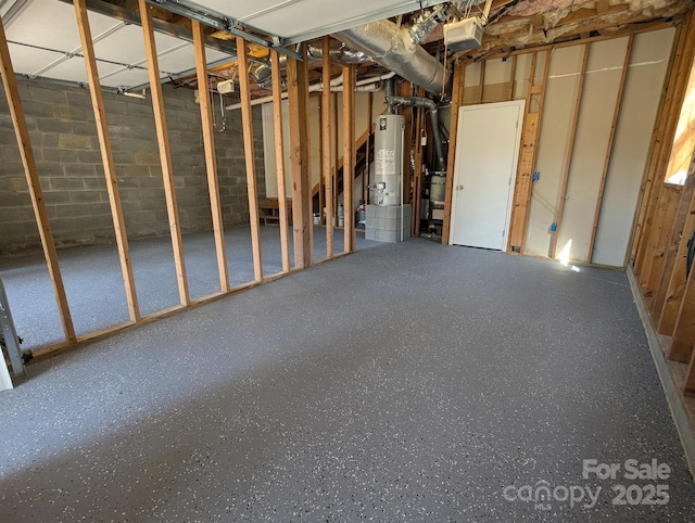 misc room with gas water heater, speckled floor, and concrete block wall