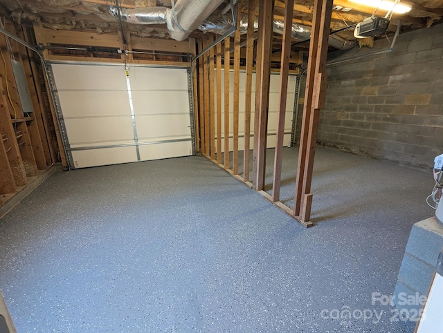 garage featuring concrete block wall and a garage door opener