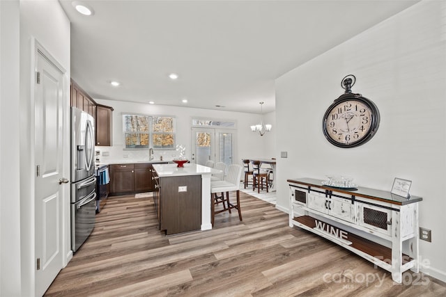 kitchen with a kitchen breakfast bar, hardwood / wood-style floors, a notable chandelier, a kitchen island, and decorative light fixtures