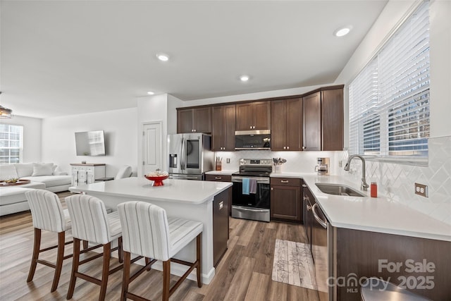 kitchen with stainless steel appliances, tasteful backsplash, hardwood / wood-style floors, a kitchen island, and sink