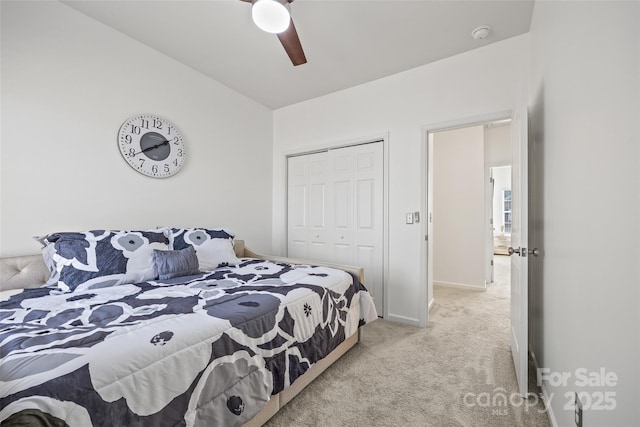 bedroom with light colored carpet, ceiling fan, and a closet