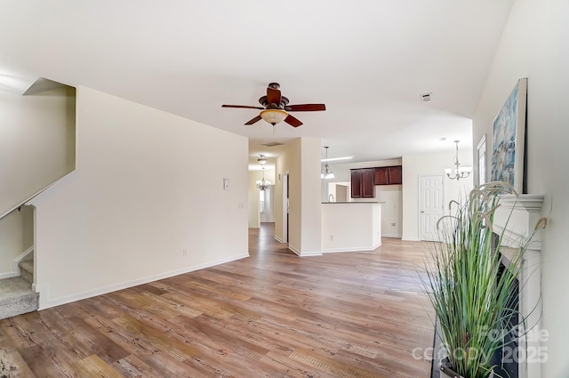 unfurnished living room featuring ceiling fan with notable chandelier and hardwood / wood-style flooring