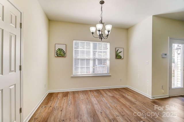 unfurnished dining area with light hardwood / wood-style floors, a wealth of natural light, and a chandelier