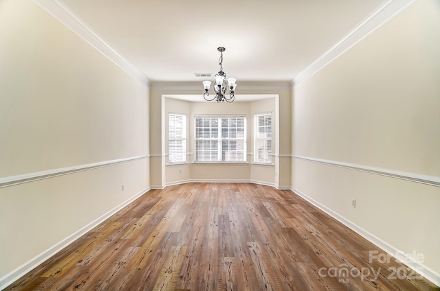 unfurnished dining area with hardwood / wood-style flooring, crown molding, and an inviting chandelier