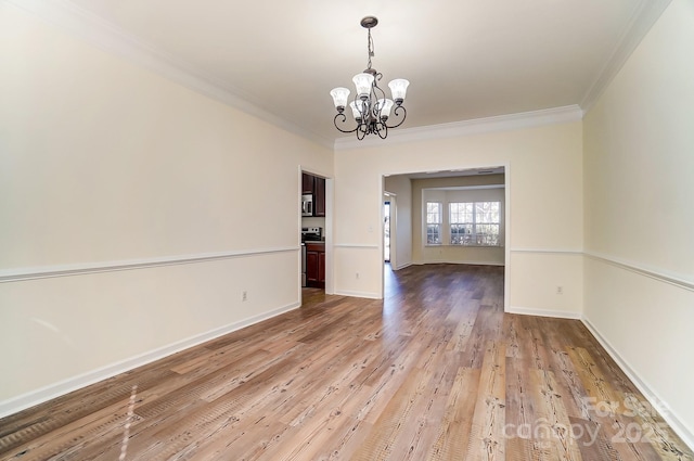 unfurnished dining area featuring ornamental molding, light wood-type flooring, and an inviting chandelier