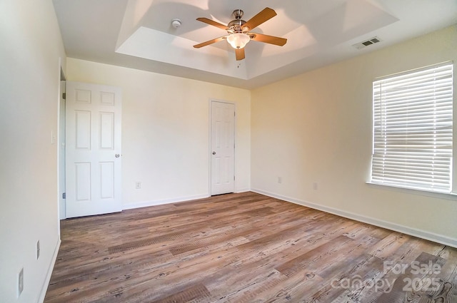 unfurnished room with a tray ceiling, ceiling fan, and hardwood / wood-style flooring