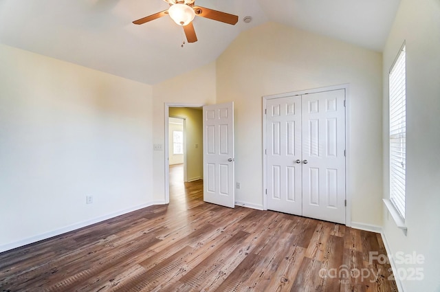 unfurnished bedroom with wood-type flooring, a closet, ceiling fan, and lofted ceiling