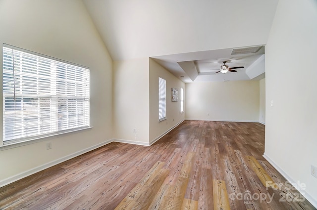 unfurnished living room featuring a raised ceiling, ceiling fan, and hardwood / wood-style floors