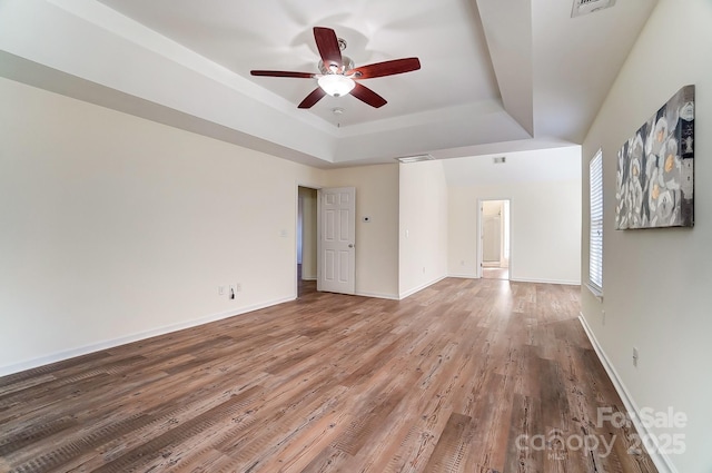 unfurnished room featuring hardwood / wood-style flooring, ceiling fan, and a raised ceiling