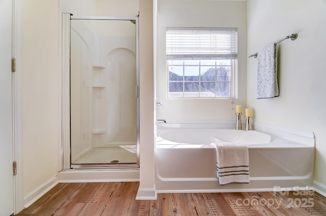 bathroom with shower with separate bathtub and wood-type flooring